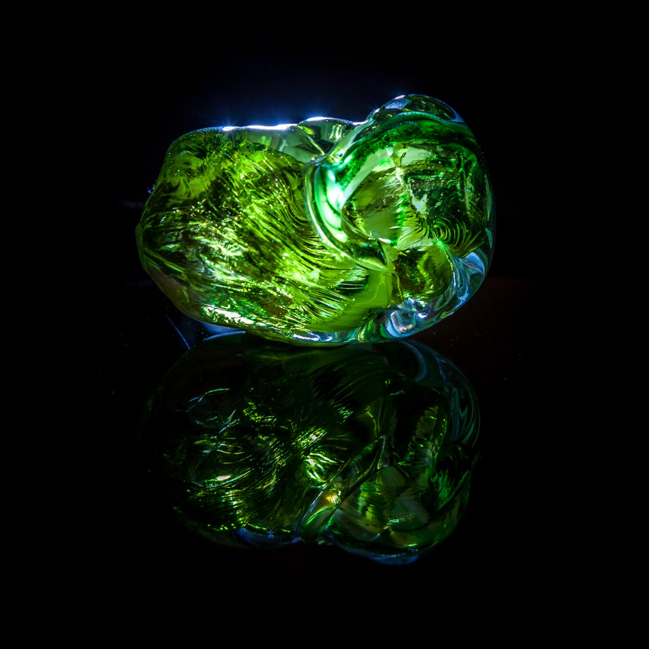Leuchtend grüner Glasklumpen aus Lauscha im Durchlicht